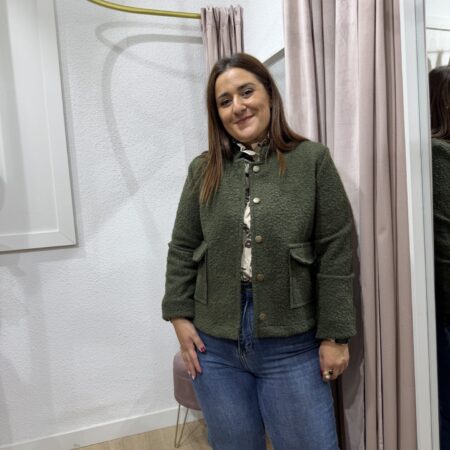 Chaqueta lanosa de estilo Chanel en tono verde caqui con bolsillos frontales y textura bouclé combinada con pantalón vaquero.